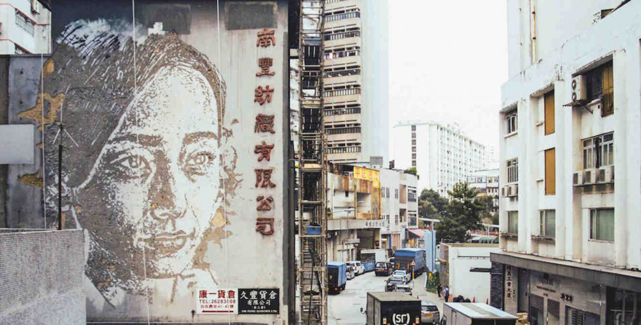 Factory Worker, by Alexandre Farto  Hong Kong, China
Portuguese artist Alexandre Farto, aka Vhils, does not paste or paint to create his street art; instead he chisels and chips, stripping away layers of walls to create large-scale bas-relief images. In 2015, he applied his technique in Hong Kong to create a portrait of a female factory worker on the exterior of a local textiles plant, now an arts centre.
